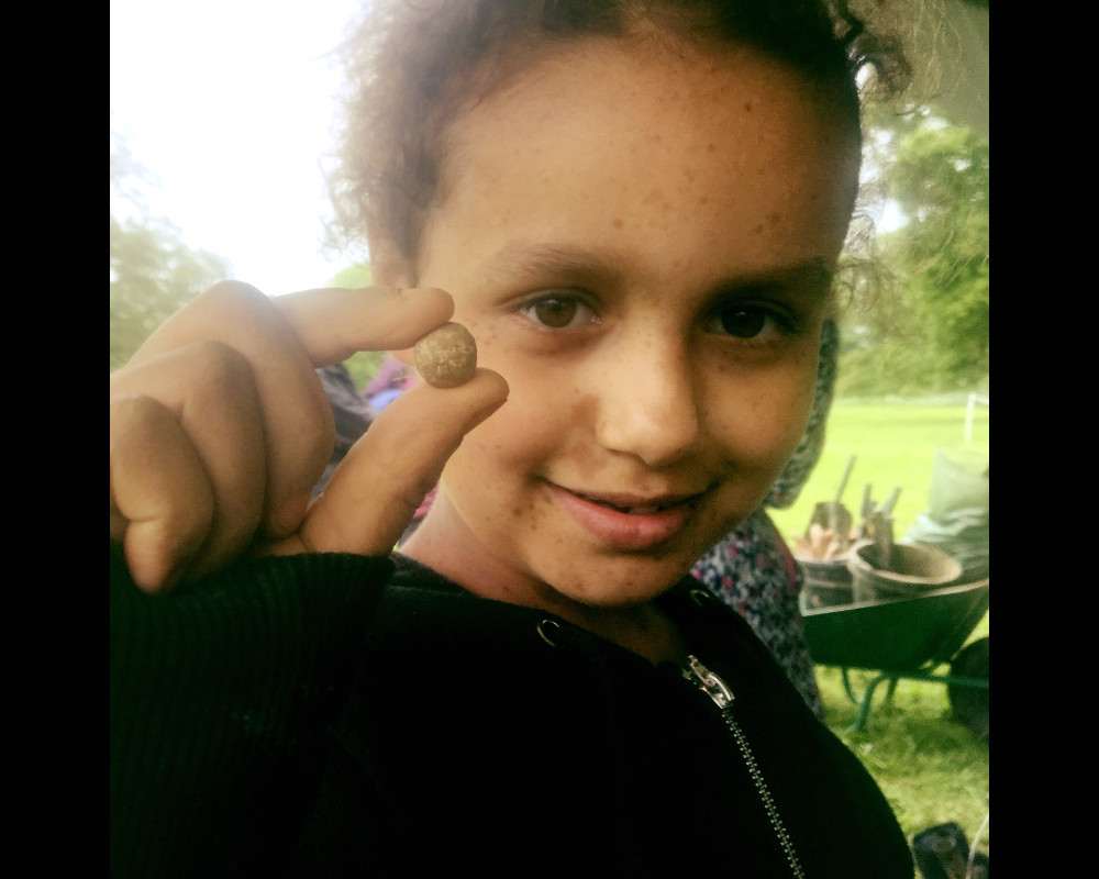 photo of a young girl dig volunteer holding pistol ball