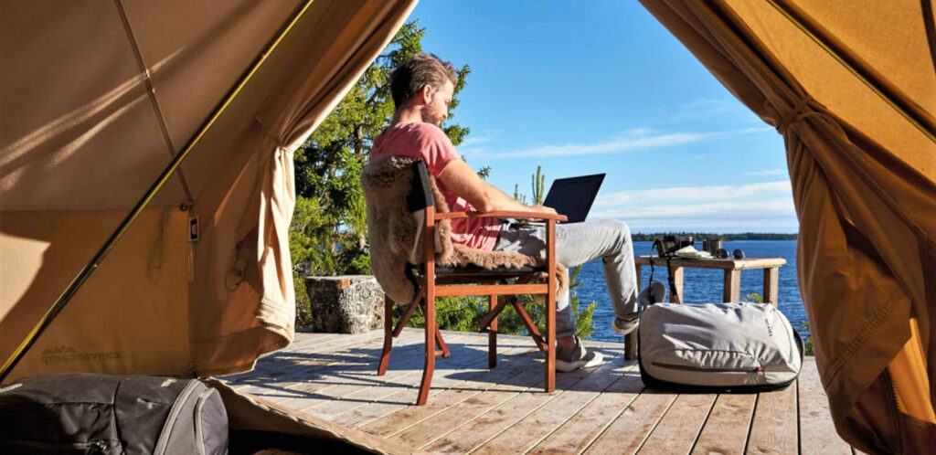 Photo of a man in a glam tent working on a lap top