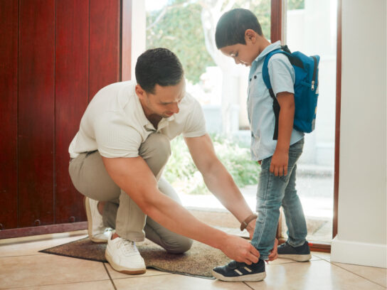 photo of father and son adjusting shoes at home getting ready for school