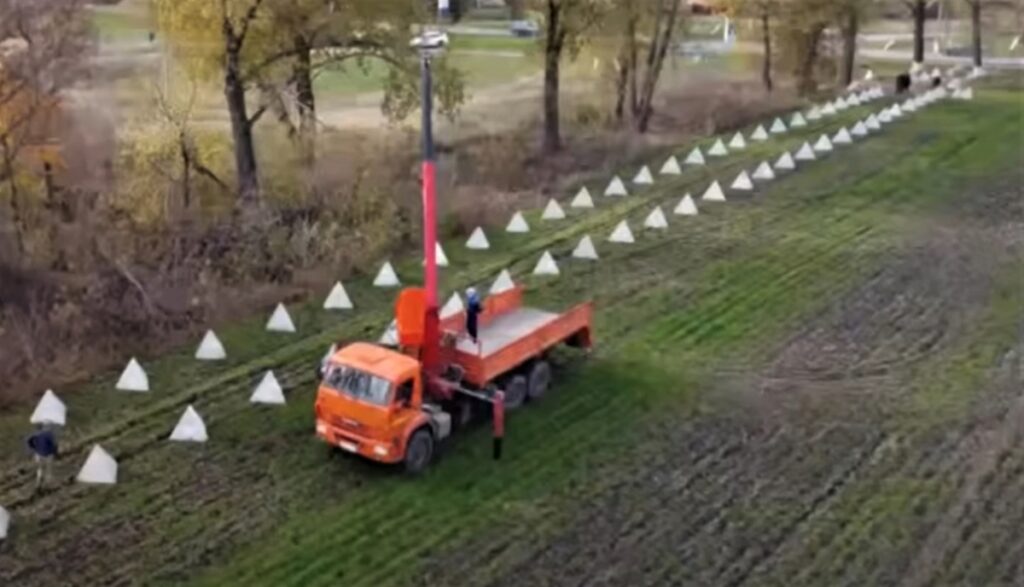 photo of a Russian vehicle laying dragons’ teeth. Dragon’s teeth are usually about 3-4 feet tall, pyramid shaped, and made of concrete. The Russian type is usually not anchored in a concrete mat or deep in the ground, and hence is not as effective as the WW II version. The Russian version is designed to tip under the tank and force it up in the air, losing traction, slowing it, and making its underbelly vulnerable to an RPG.