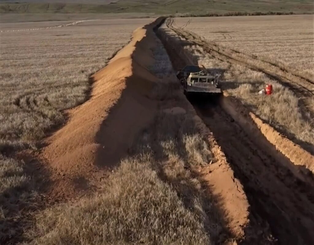 photo of a Russian anti-tank ditch in eastern Ukraine. This barrier appears to be only about 10 feet wide and 5 feet deep, with soft soil on both sides, and hence could be filled in in a few minutes by an advanced AEV. It might even be narrow enough to be cross-able by a main battle tank (which would be coming in from the right), either slowly dipping down into it and pushing through and up the soft soil on the left side, or traveling at speed and jumping the ditch. An effective ditch should be much wider and deeper.