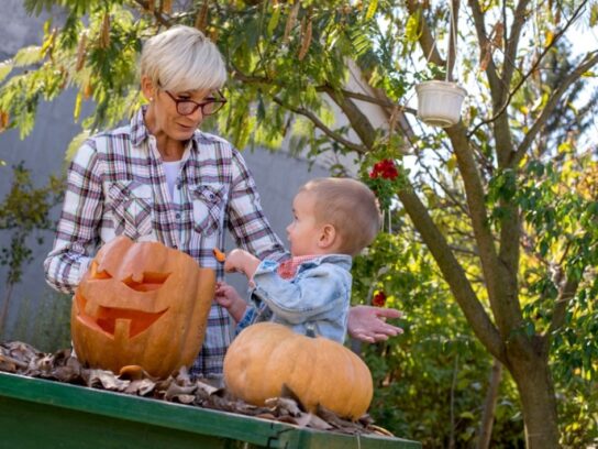 photo of grandmother with toddler working on carving a pumpkin