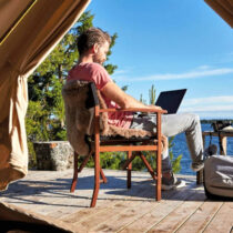 Photo of a man in a glam tent working on a lap top