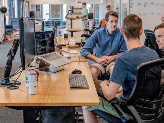 photo of modern casual workplace with three men at work table talking