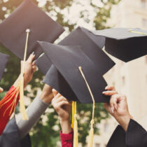 photo of group of graduates throwing graduation caps in the air