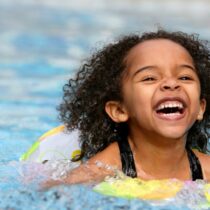 photo of jubilant kid swimming in a pool