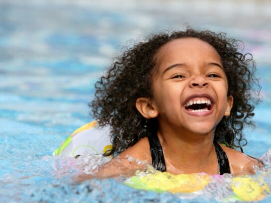 photo of jubilant kid swimming in a pool