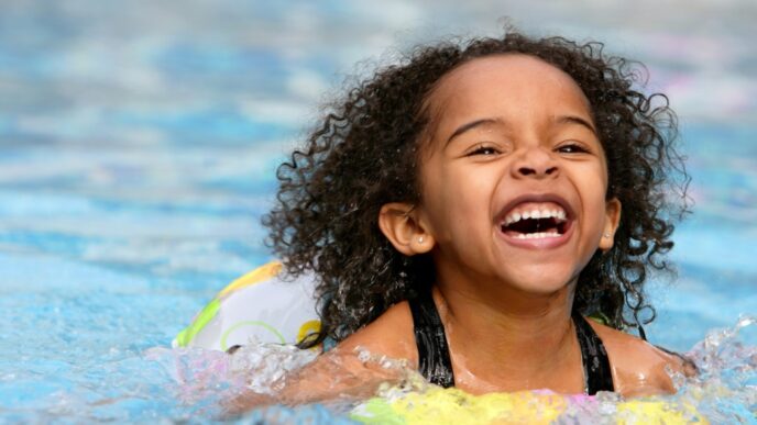 photo of jubilant kid swimming in a pool