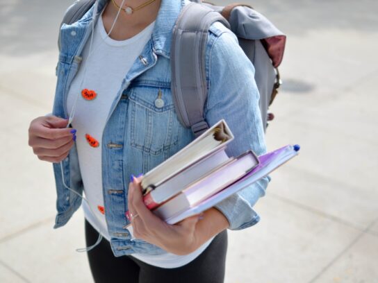 Student with backpack on holding books in their hand.