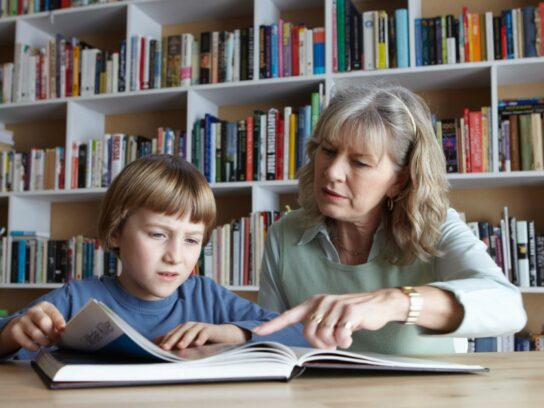 photo of woman and grandson reading together in library