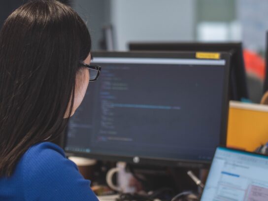 photo of women looking at laptop and monitor