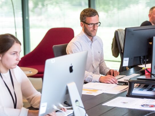 photo of young adults working on pcs or macs