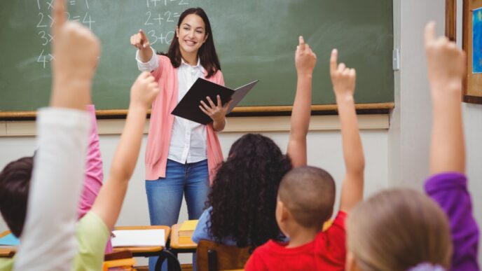 photo of teacher in front of class with students with raised hands