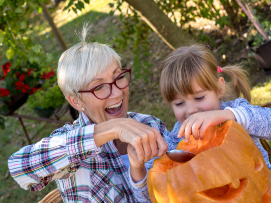 grandparent and grandchild carving jack-o-lantern