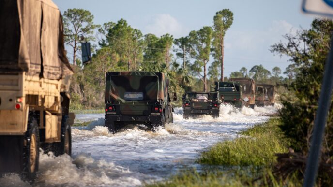 Florida National Guard vehicles mobilizing over a flooded road to provide aid for Hurricane Helene victims.