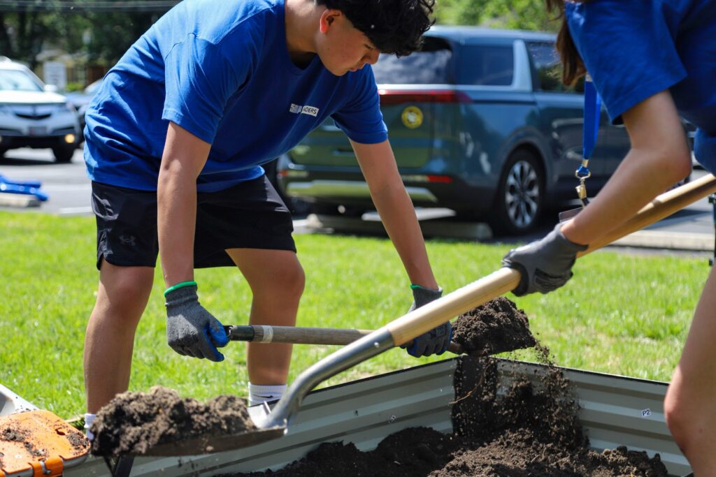 Students and volunteers build garden beds and prepare a possible fire pit area