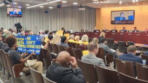 A packed hearing room with residents holding signs opposing data centers during a Montgomery County Council vote.