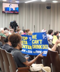 A sign reading "We Can't Drink Data" held up during a Montgomery County Council meeting.