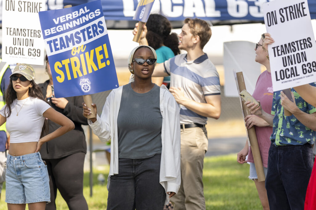 A striking worker holds a sign and chants outside Verbal Beginnings in Rockville.