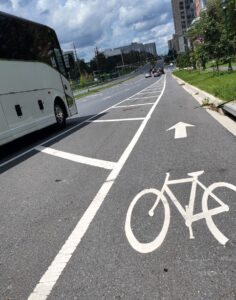 Bike lane painted with white lines alongside a bus on Old Georgetown Road near Executive Boulevard.