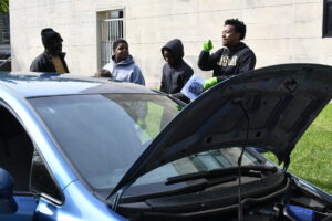 Alpha Phi Alpha member shows Montgomery County Scouts the engine of a car during a hands-on class at Alpha Merit Badge University.