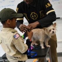 A Scout in uniform works with an Alpha Phi Alpha member during a veterinary medicine merit badge class at Alpha Merit Badge University.
