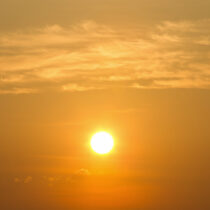Hazy orange sky with the sun low and bright, evoking Maryland's extreme summer heat.